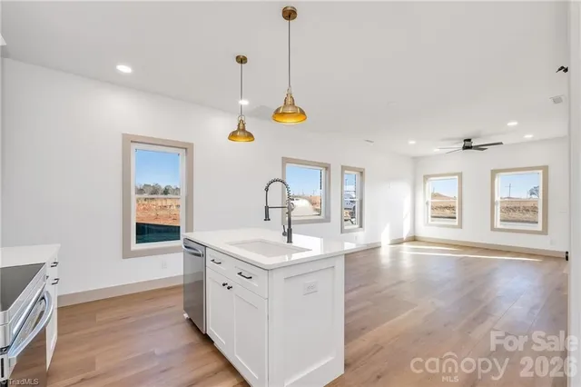 a hall with kitchen island a stove a wooden floor and a sink