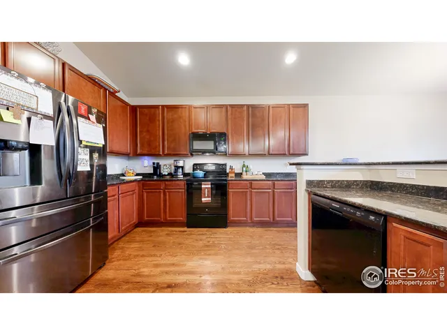 a kitchen with stainless steel appliances granite countertop a stove top oven a sink and a refrigerator