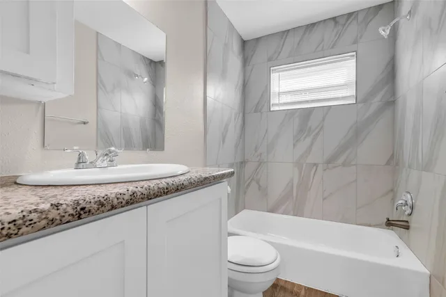 a bathroom with a granite countertop sink a toilet and bathtub
