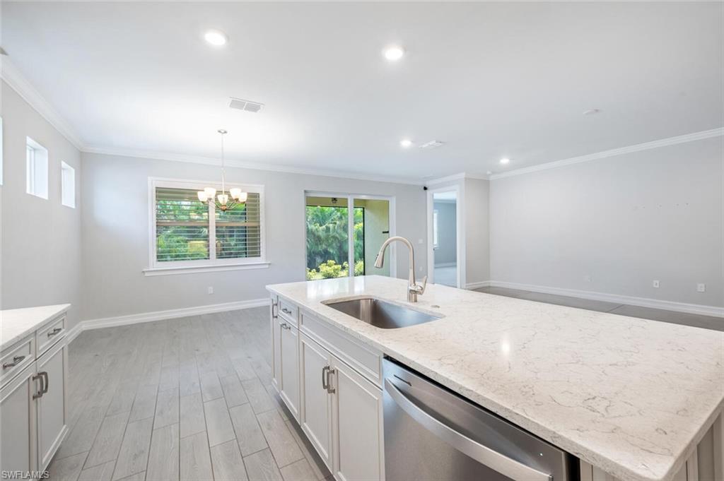 388 Grace Bay Lane Naples, FL 34114 - Photo 10 of 39 Kitchen with light wood-type flooring, white cabinetry, dishwasher, crown molding, and a center island with sink