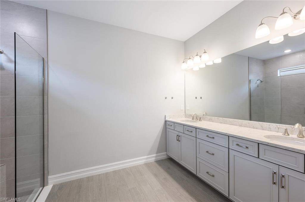 388 Grace Bay Lane Naples, FL 34114 - Photo 13 of 39 Bathroom with a walk in shower, double vanity, and light wood-type flooring