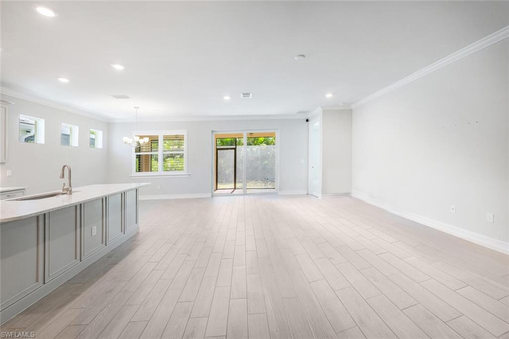 388 Grace Bay Lane Naples, FL 34114 - Photo 2 of 39 Unfurnished living room with crown molding, light wood-style flooring, recessed lighting, and a chandelier