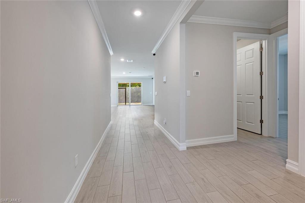 388 Grace Bay Lane Naples, FL 34114 - Photo 3 of 39 Hallway with crown molding, light wood-type flooring, and recessed lighting