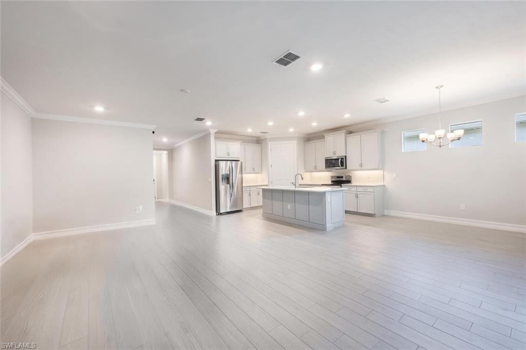 388 Grace Bay Lane Naples, FL 34114 - Photo 39 of 39 Kitchen with open floor plan, light countertops, ornamental molding, an island with sink, and appliances with stainless steel finishes