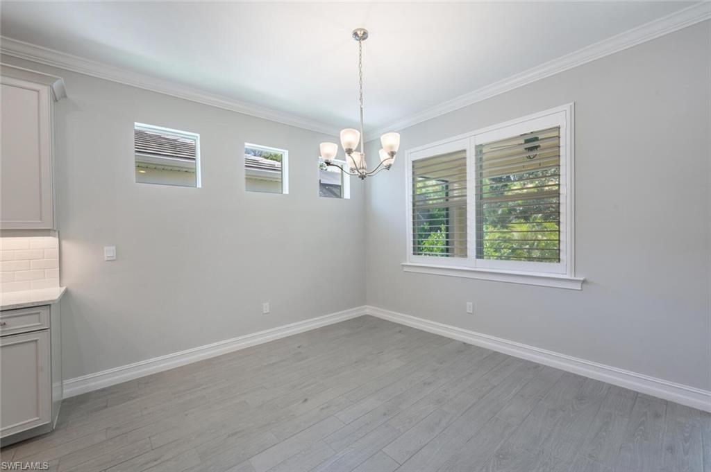 388 Grace Bay Lane Naples, FL 34114 - Photo 8 of 39 Unfurnished dining area featuring healthy amount of natural light, crown molding, light wood-style floors, and a chandelier