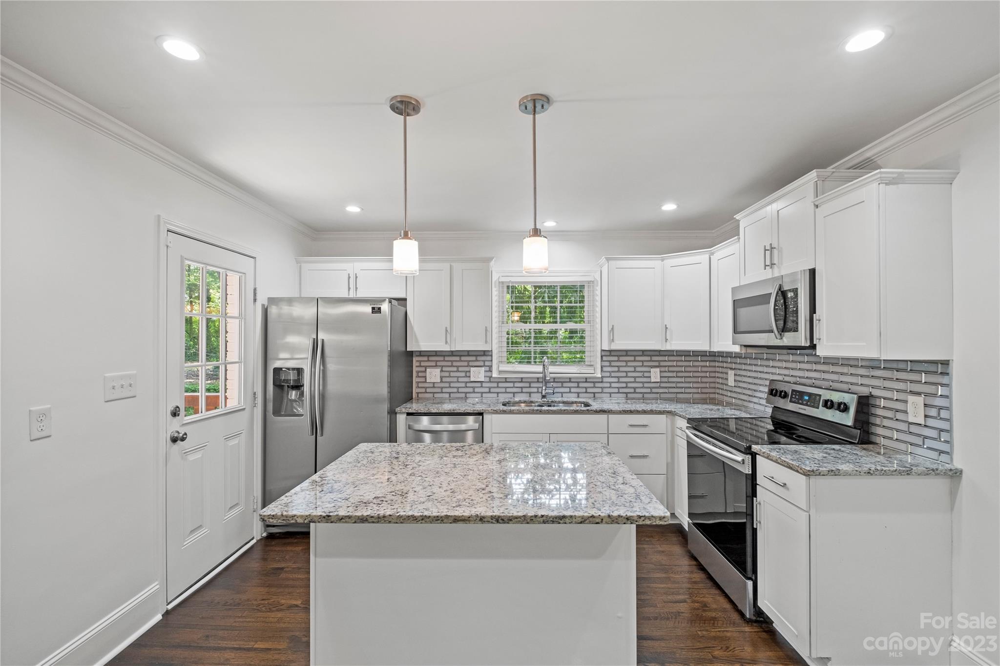3522 Enfield Road Charlotte, NC 28205 - Photo 6 of 32 a kitchen with stainless steel appliances kitchen island granite countertop a refrigerator a oven a sink and white cabinets with wooden floor