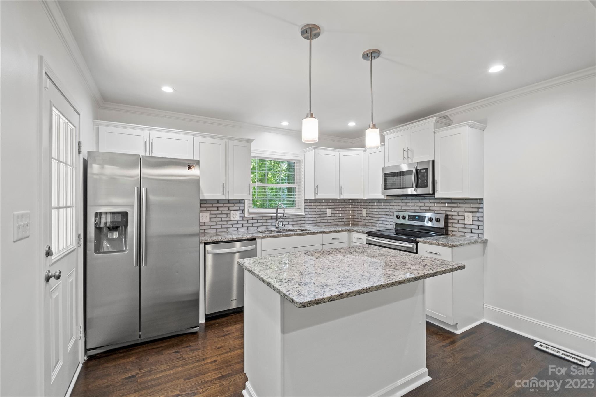 3522 Enfield Road Charlotte, NC 28205 - Photo 7 of 32 a kitchen with stainless steel appliances granite countertop a sink a stove a refrigerator a center island and cabinets