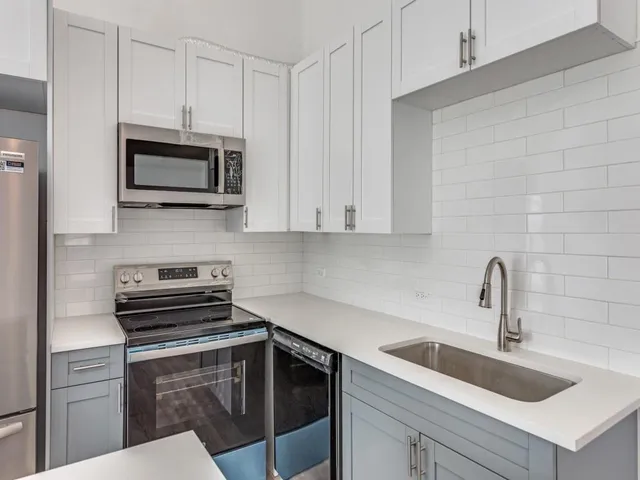 a kitchen with a sink dishwasher a stove and white cabinets with wooden floor