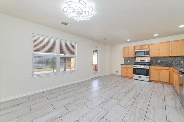 a large kitchen with stainless steel appliances granite countertop a stove a sink and a refrigerator