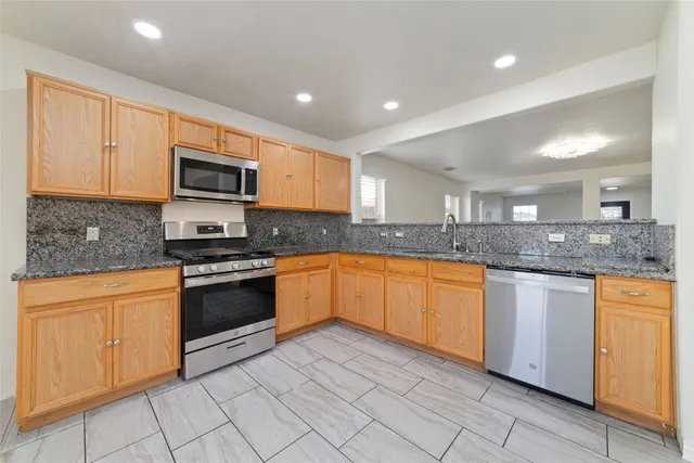 a large kitchen with granite countertop a stove top oven a sink a counter space and cabinets