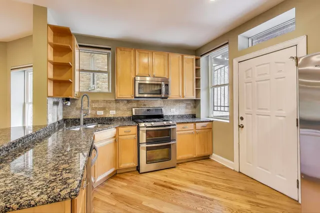 a kitchen with granite countertop a refrigerator stove top oven and sink