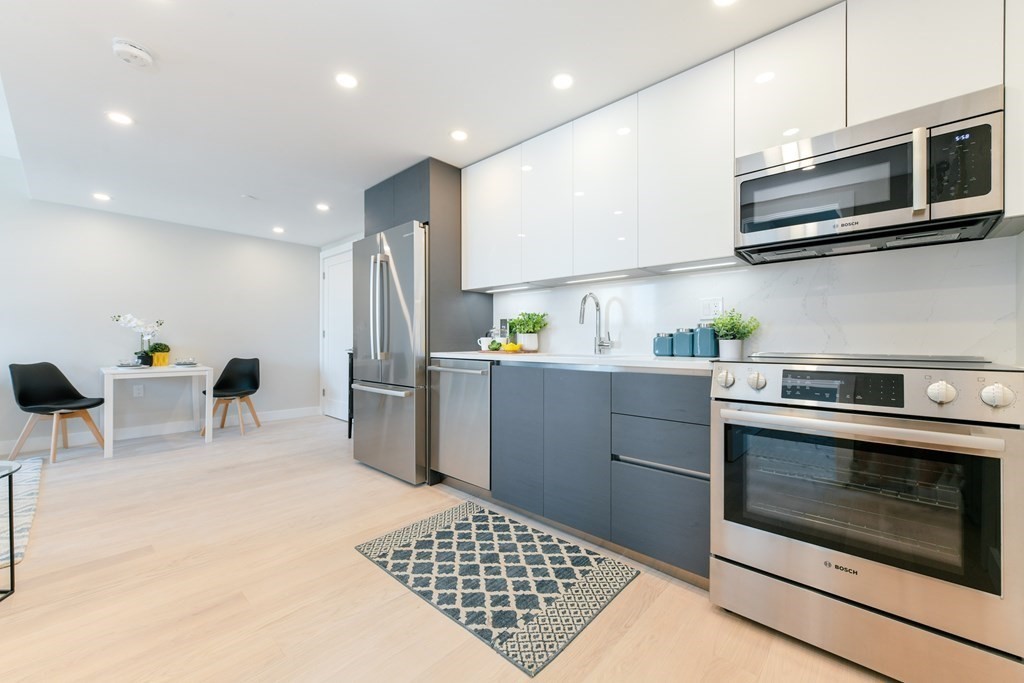 932 Broadway, Unit 212 Chelsea, MA 02150 - Photo 11 of 35 a kitchen with stainless steel appliances granite countertop a stove a microwave a sink a refrigerator white cabinets and wooden floor