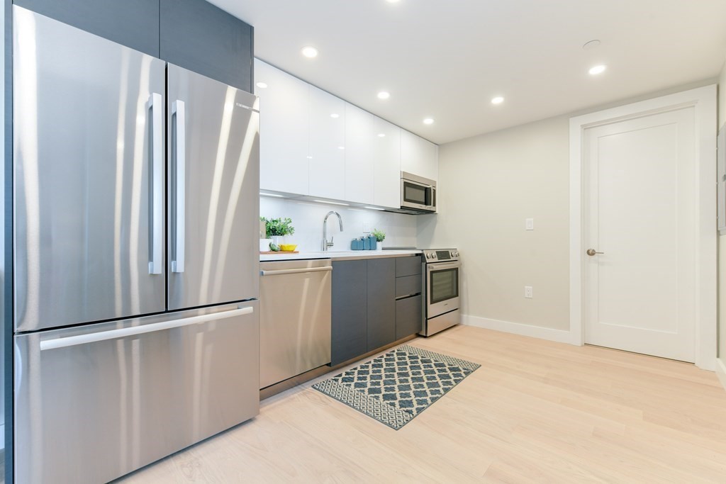 932 Broadway, Unit 212 Chelsea, MA 02150 - Photo 10 of 35 a kitchen with a refrigerator a sink and cabinets