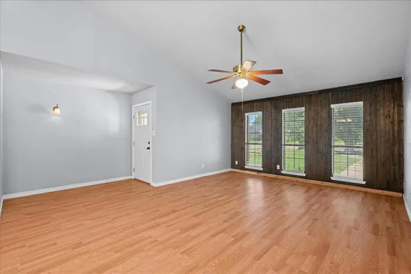 a view of an empty room with window and wooden floor