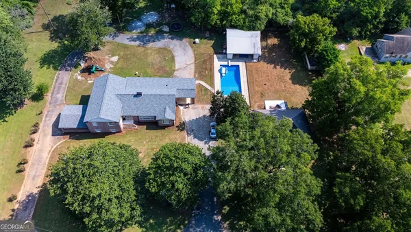 an aerial view of residential houses with outdoor space and trees all around