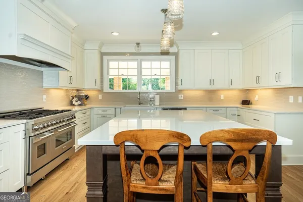 a kitchen with granite countertop a stove a sink and white cabinets