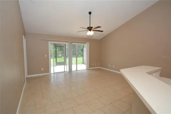 an empty room with chandelier fan and windows
