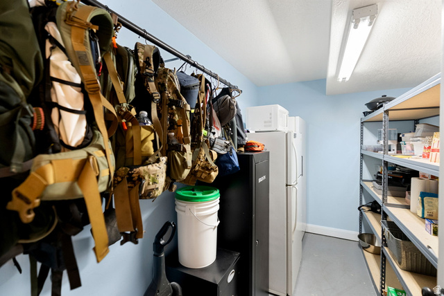 2485 South 1100th Street West Logan, UT 84321 - Photo 34 of 53 Dedicated storage area featuring expansive shelving units, two full-size refrigerators, and overhead fluorescent lighting