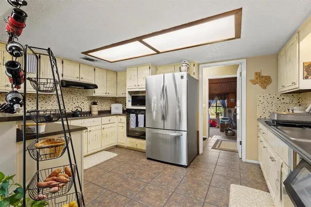 a kitchen with stainless steel appliances granite countertop a refrigerator a stove and a sink