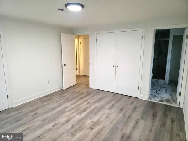 a view of an empty room with wooden floor and closet
