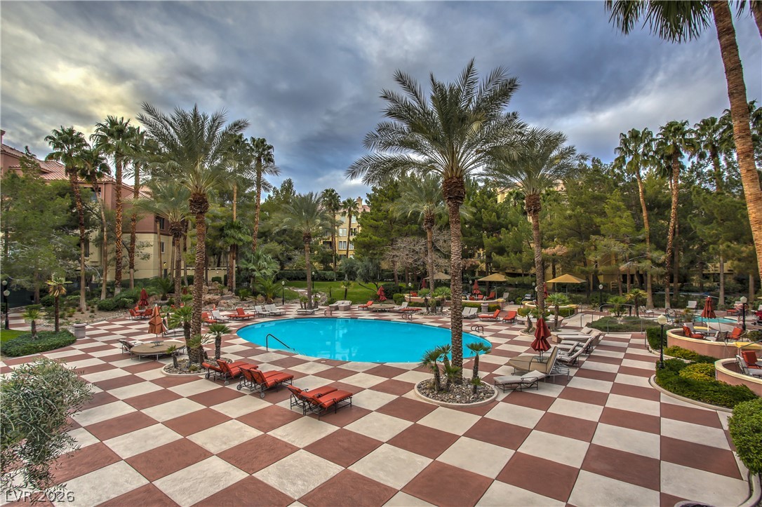 210 East Flamingo Road, Unit 208 Las Vegas, NV 89169 - Photo 37 of 42 An inviting oasis with a shimmering pool, surrounded by mature palm trees and ample lounging areas.