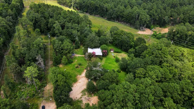 an aerial view of residential house with outdoor space and trees all around