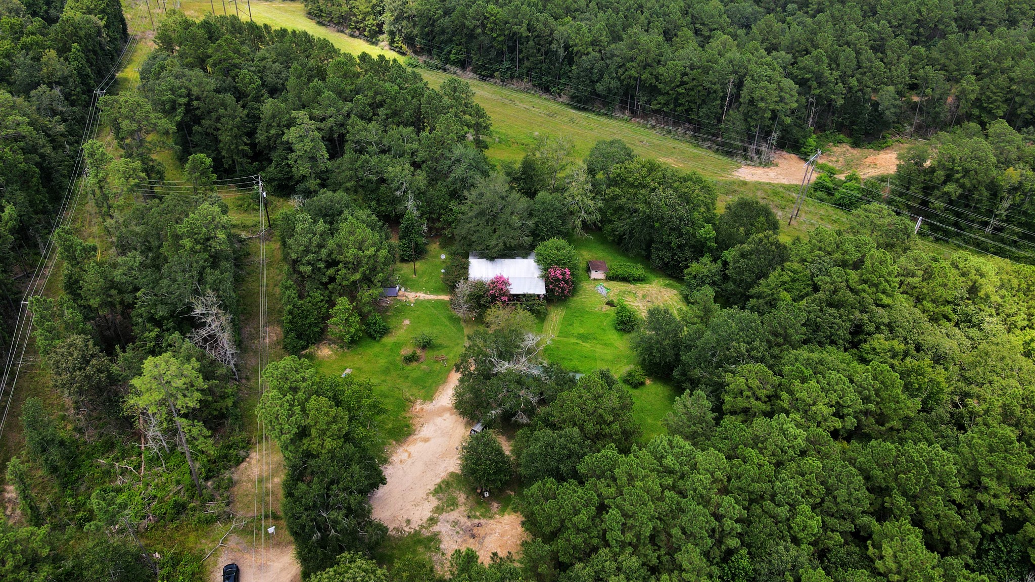 an aerial view of residential house with outdoor space and trees all around