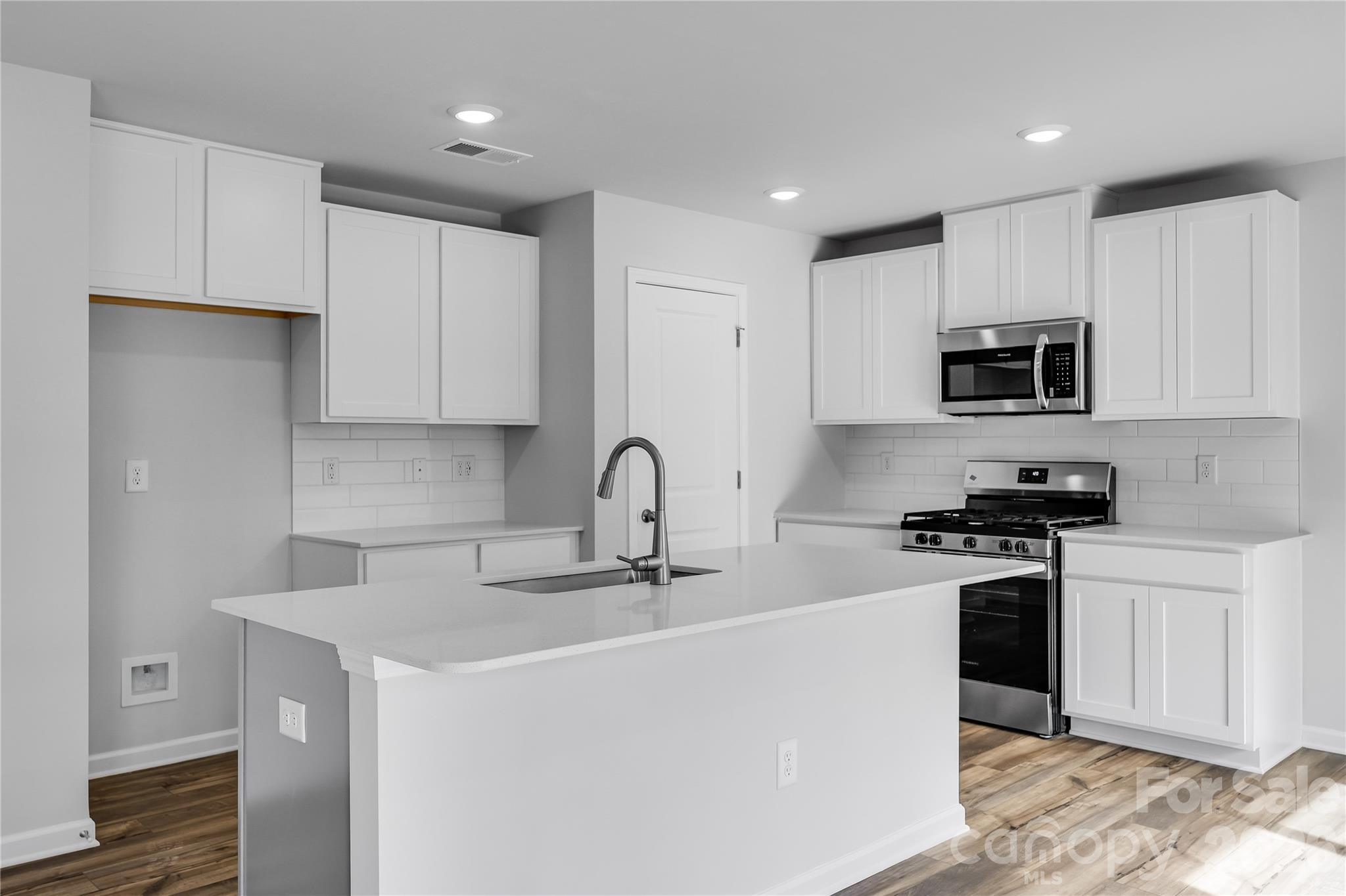 233 West 18th Street Kannapolis, NC 28081 - Photo 13 of 27 a kitchen with stainless steel appliances granite countertop a stove top oven a sink a refrigerator and white cabinets with wooden floor