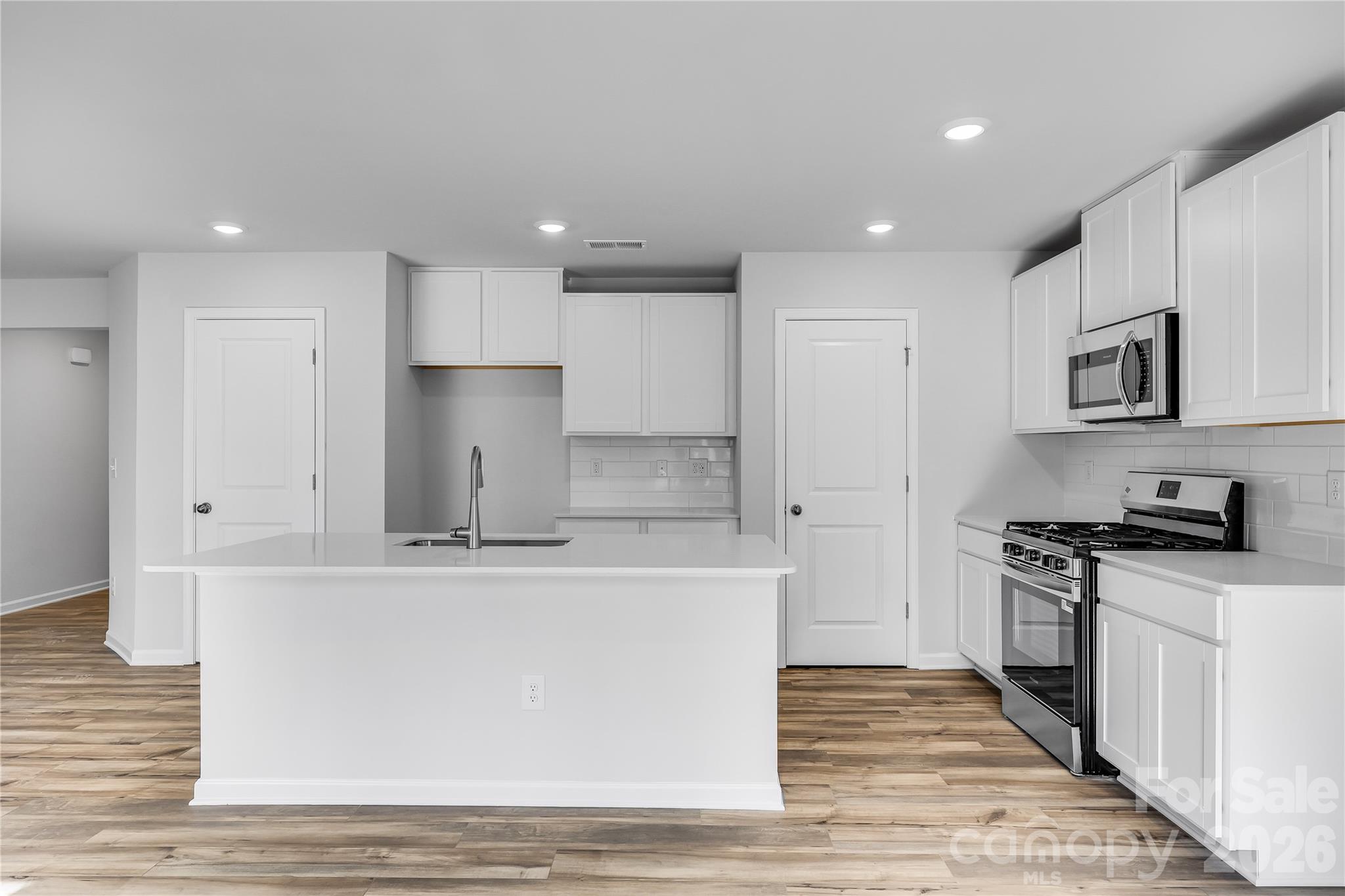 233 West 18th Street Kannapolis, NC 28081 - Photo 10 of 27 a large kitchen with stainless steel appliances granite countertop a stove a sink a refrigerator and white cabinets with wooden floor