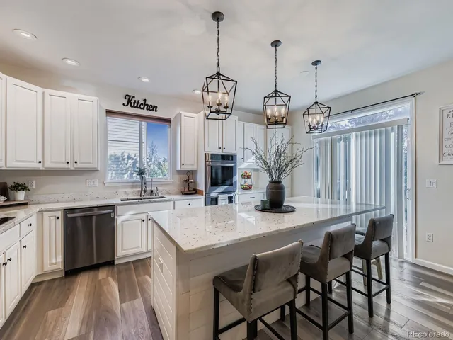 a kitchen with stainless steel appliances granite countertop a sink a stove and a wooden floors