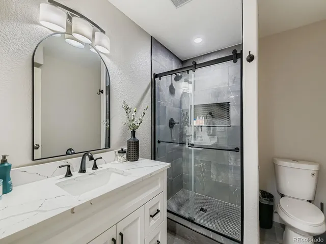 a bathroom with a shower sink mirror and toilet