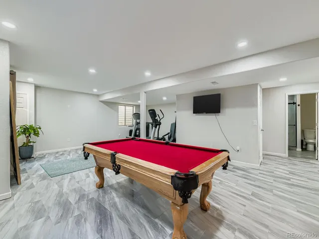 a room with wooden floor pool table and windows