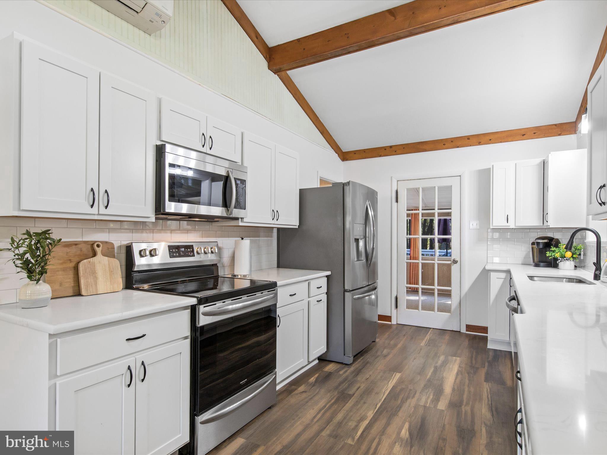 26905 Mt Vernon Road Princess Anne, MD 21853 - Photo 12 of 74 a kitchen with stainless steel appliances a stove a sink a refrigerator white cabinets and wooden floor