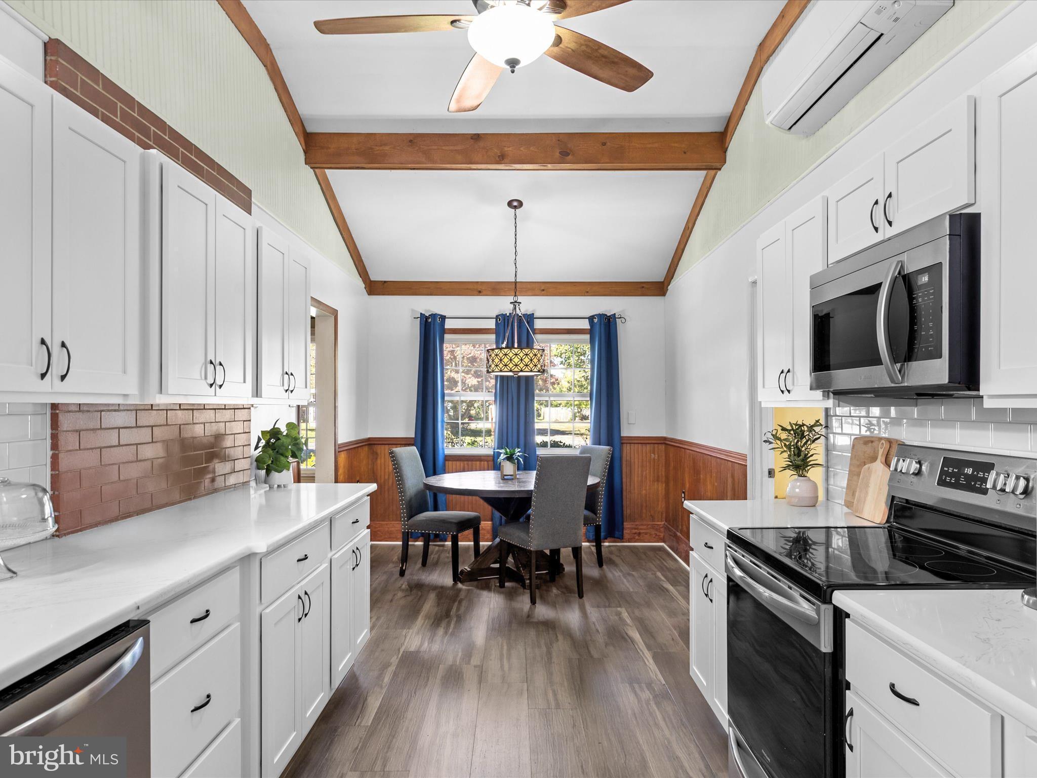 26905 Mt Vernon Road Princess Anne, MD 21853 - Photo 14 of 74 a kitchen with stainless steel appliances a stove a sink dishwasher a dining table and chairs with wooden floor