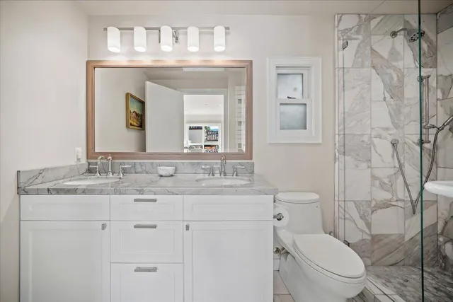 a bathroom with a granite countertop toilet sink and mirror