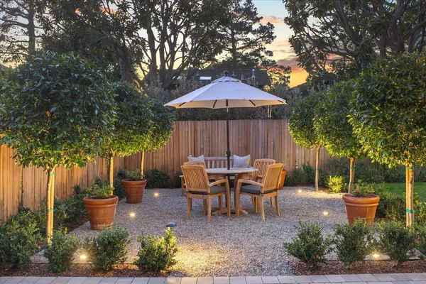 a patio table and chairs with potted plants and a barbeque