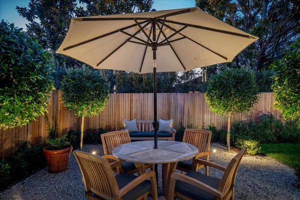 a backyard of a house with table and chairs under an umbrella