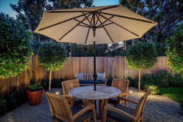 a backyard of a house with table and chairs under an umbrella