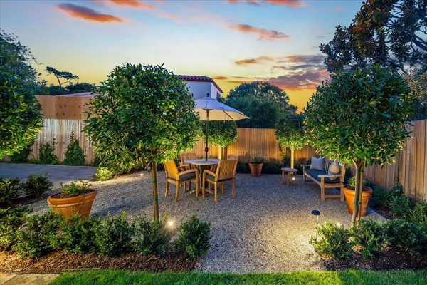 a view of a patio with table and chairs potted plants and large tree