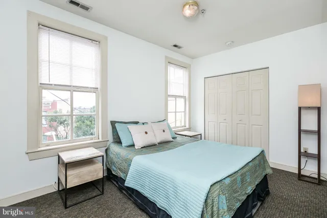 an empty room with windows and chandelier fan