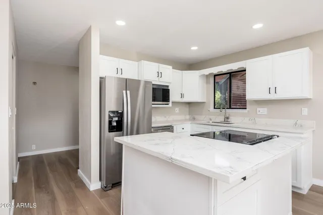 a kitchen with granite countertop white cabinets and black appliances