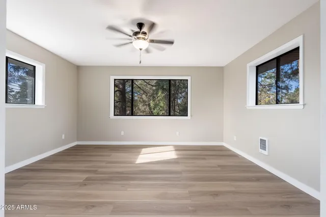 a view of empty room with wooden floor and fan