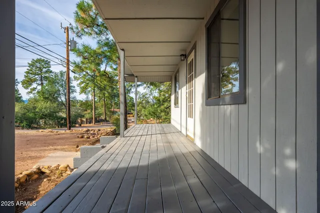 an empty room with wooden floor chandelier fan and windows