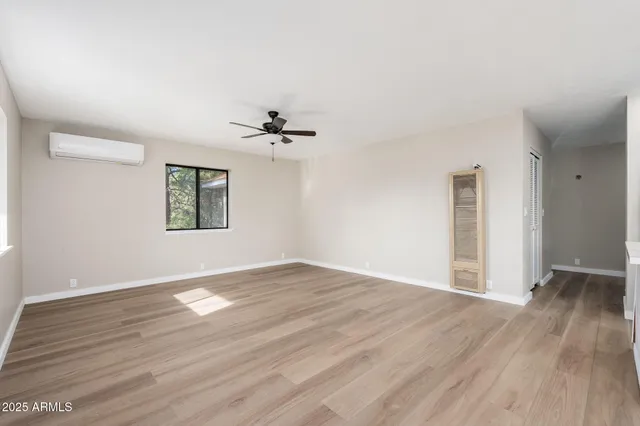 a view of an empty room with a window and wooden floor