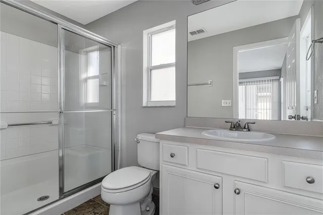 a bathroom with a granite countertop sink toilet a mirror and shower