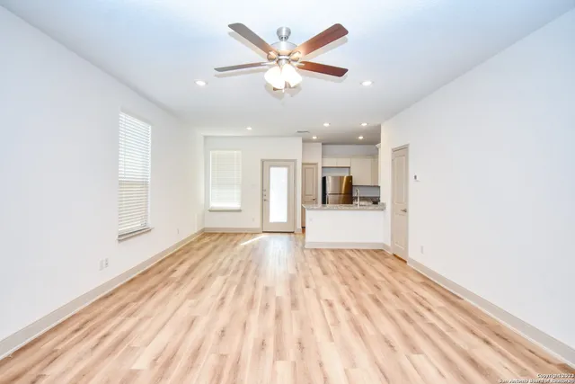 a view of empty room with wooden floor and ceiling fan