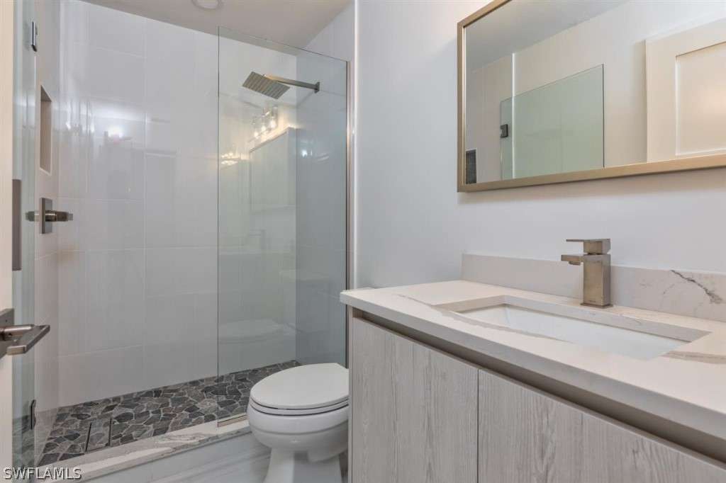 8856 Ventura Way Naples, FL 34109 - Photo 23 of 34 a bathroom with a granite countertop sink a toilet and a mirror