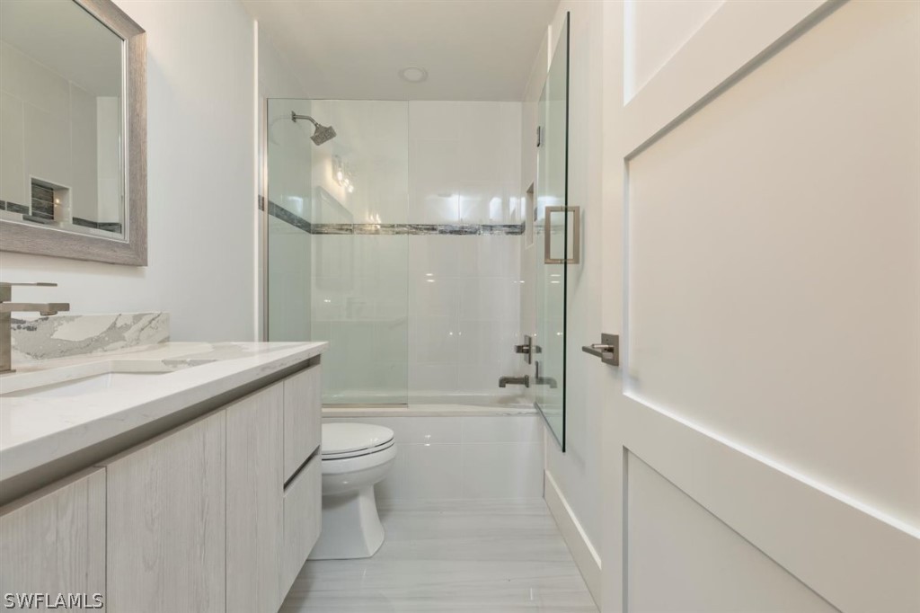 8856 Ventura Way Naples, FL 34109 - Photo 26 of 34 a bathroom with a granite countertop sink a toilet and shower