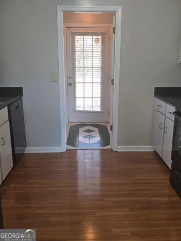 a view of an empty room with window and wooden floor