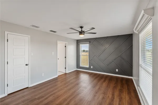 a view of an empty room with wooden floor and a window
